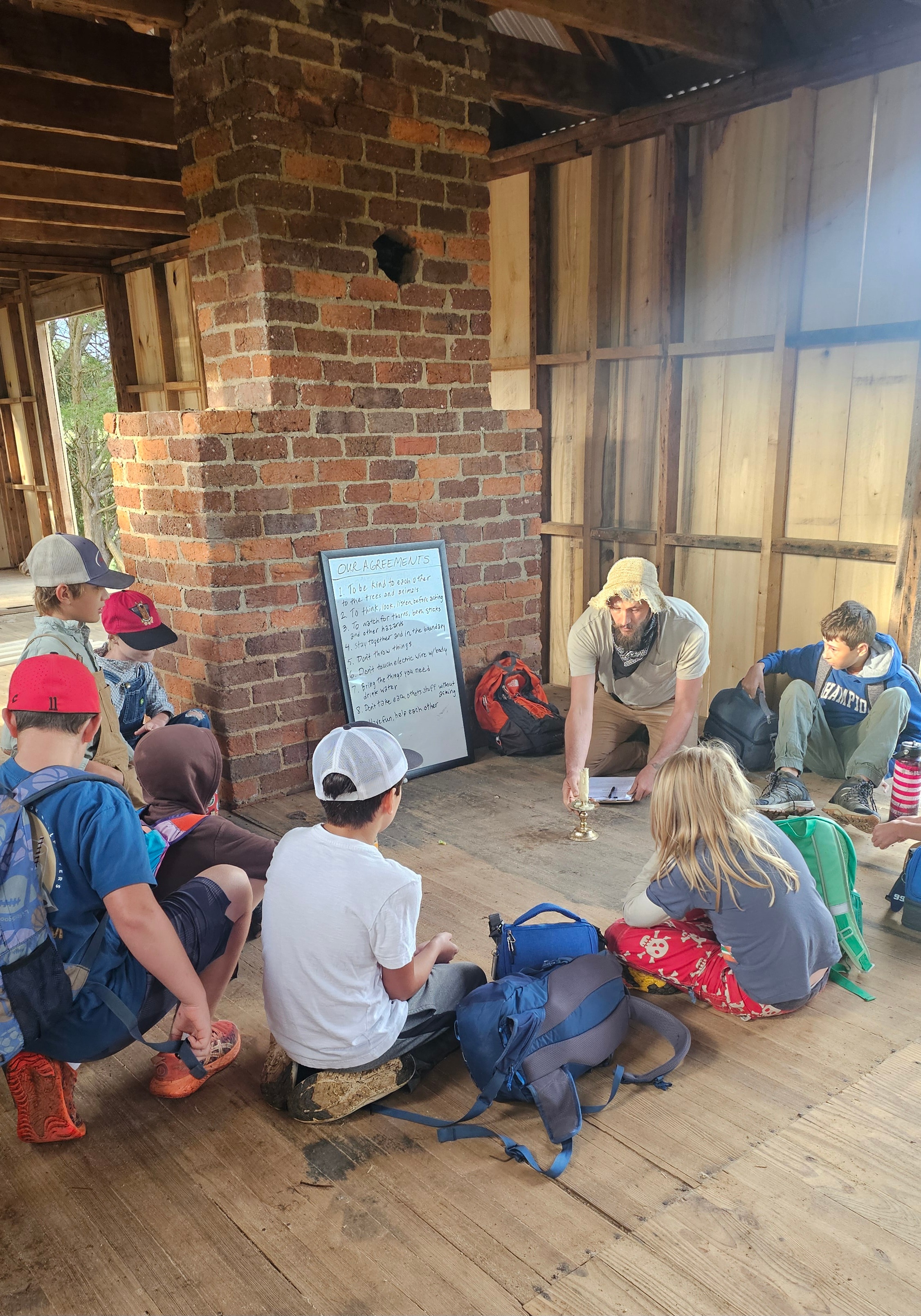 Students gathered in a circle with their guide reviewing Our Agreements inside the barn