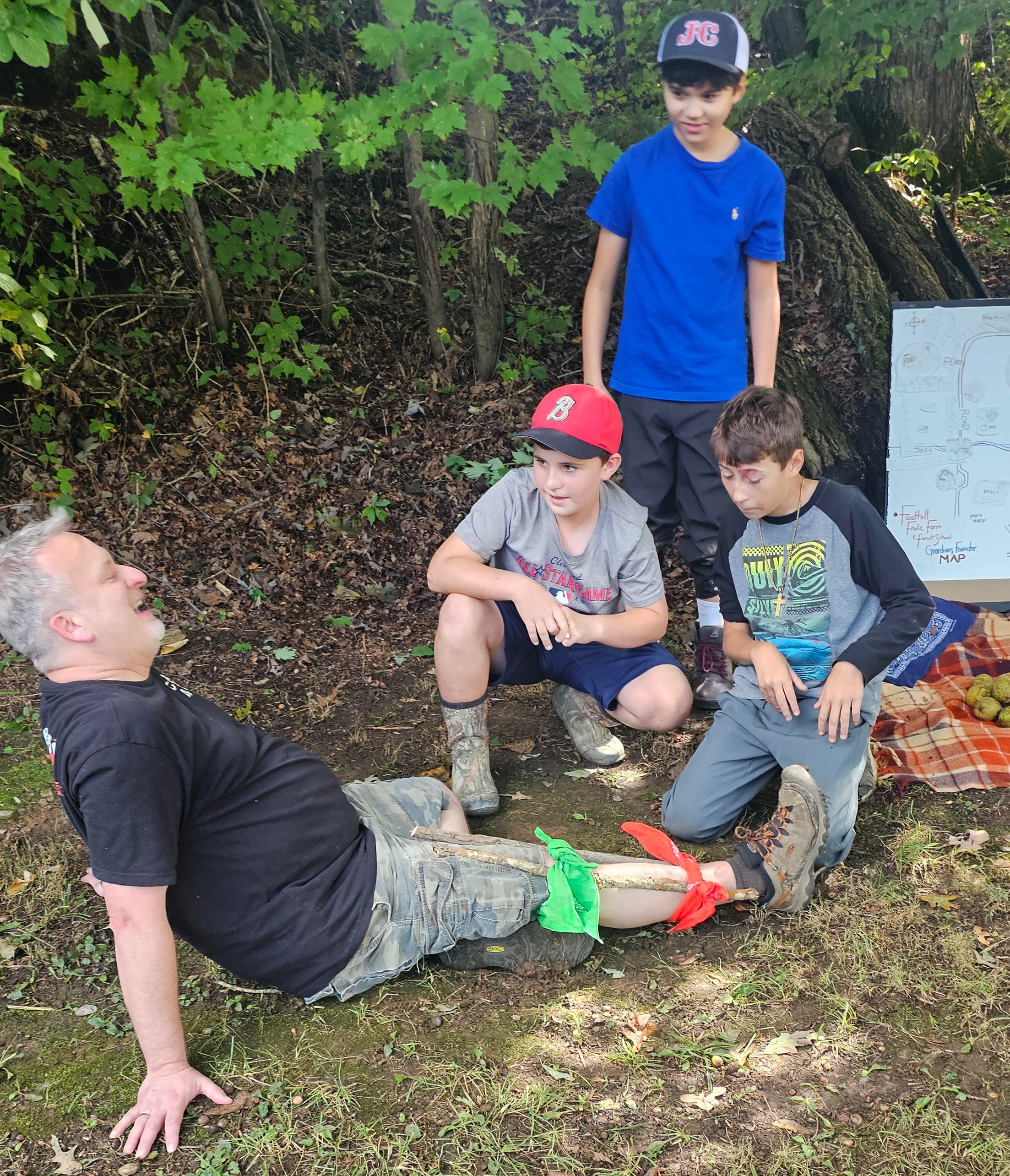 Students learning first aid splinting technique with a guide in the woods