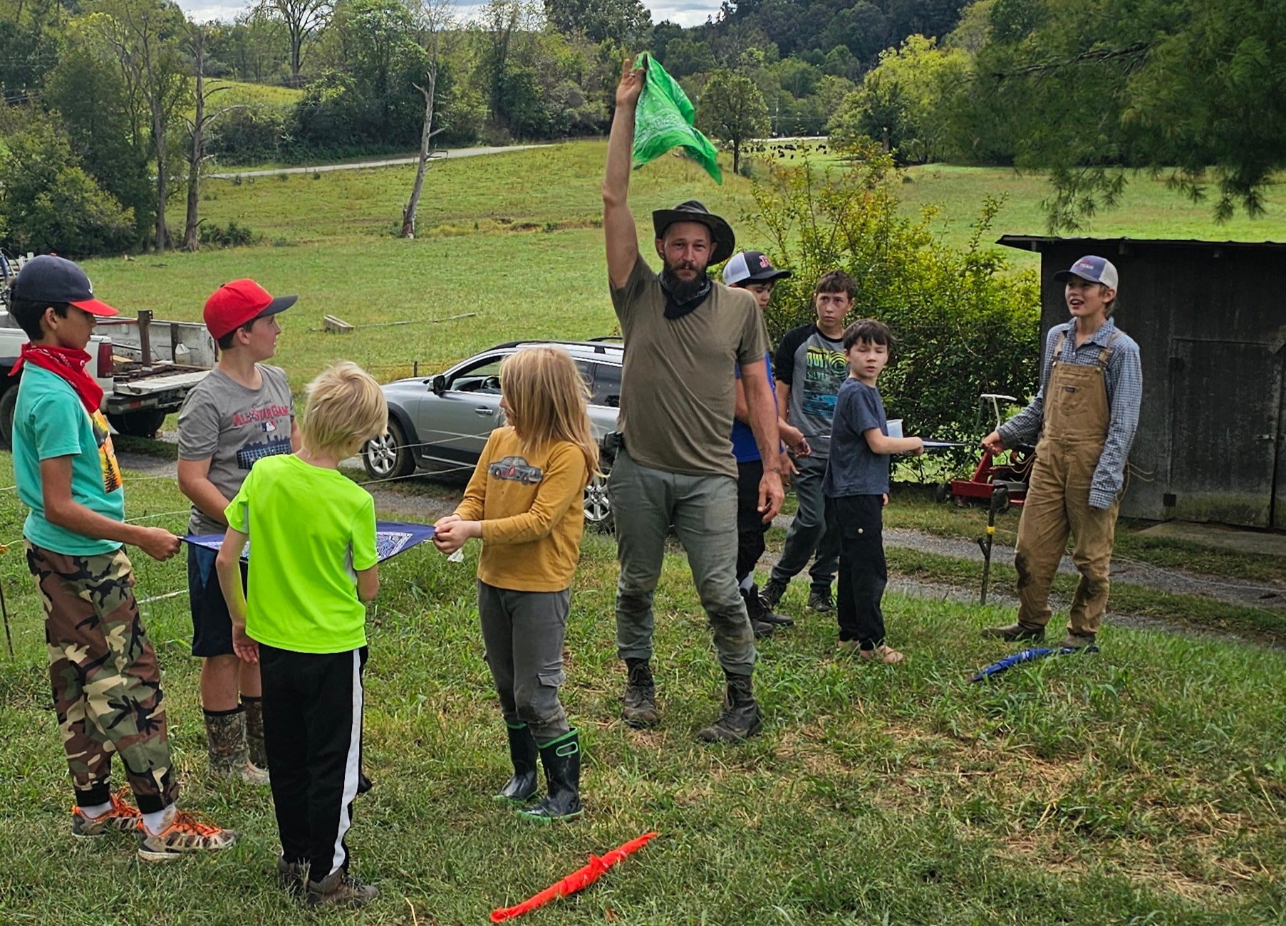 Guide raising a green flag while students gather around for an outdoor activity on the farm