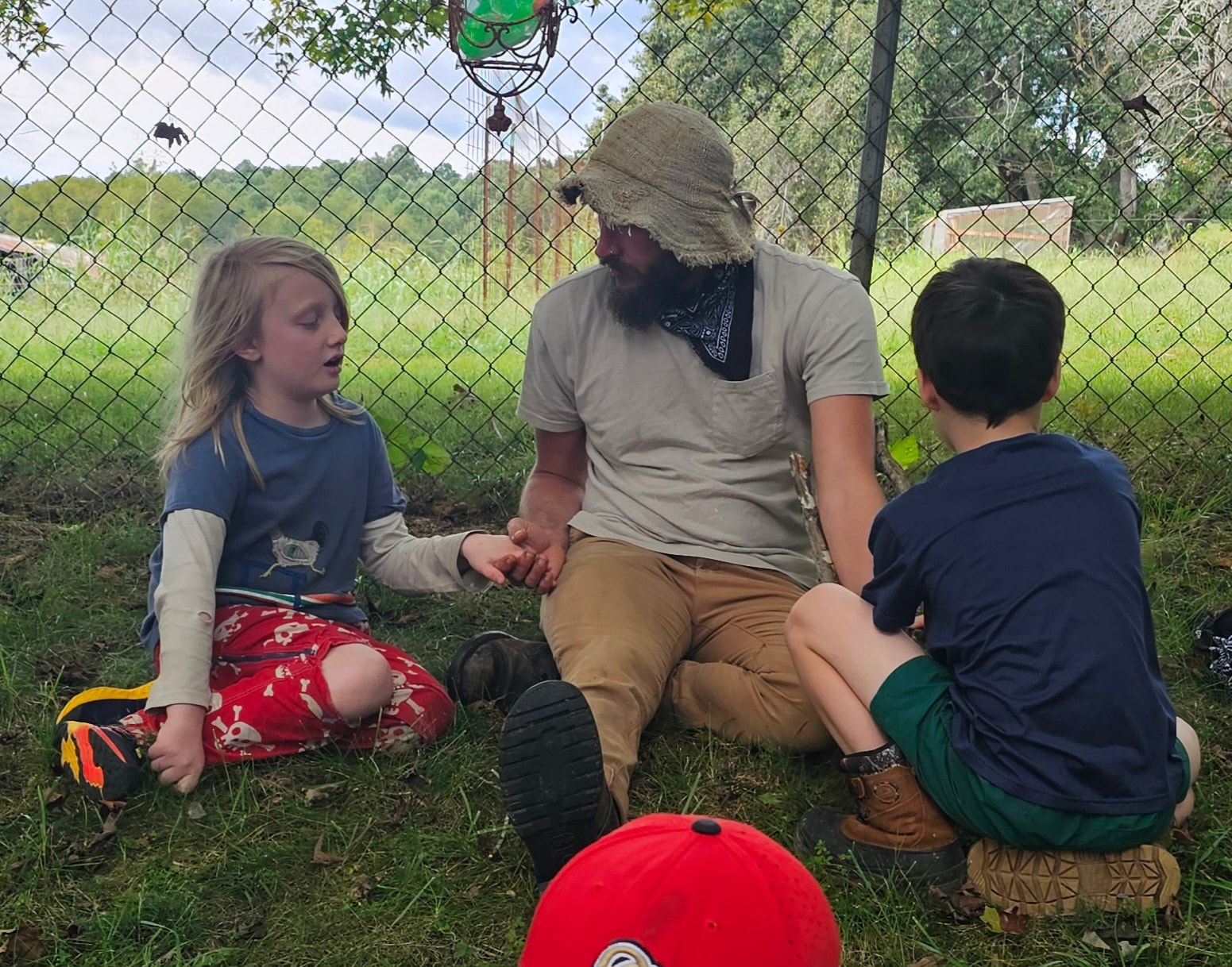 Guide sitting in the grass in conversation with two young students