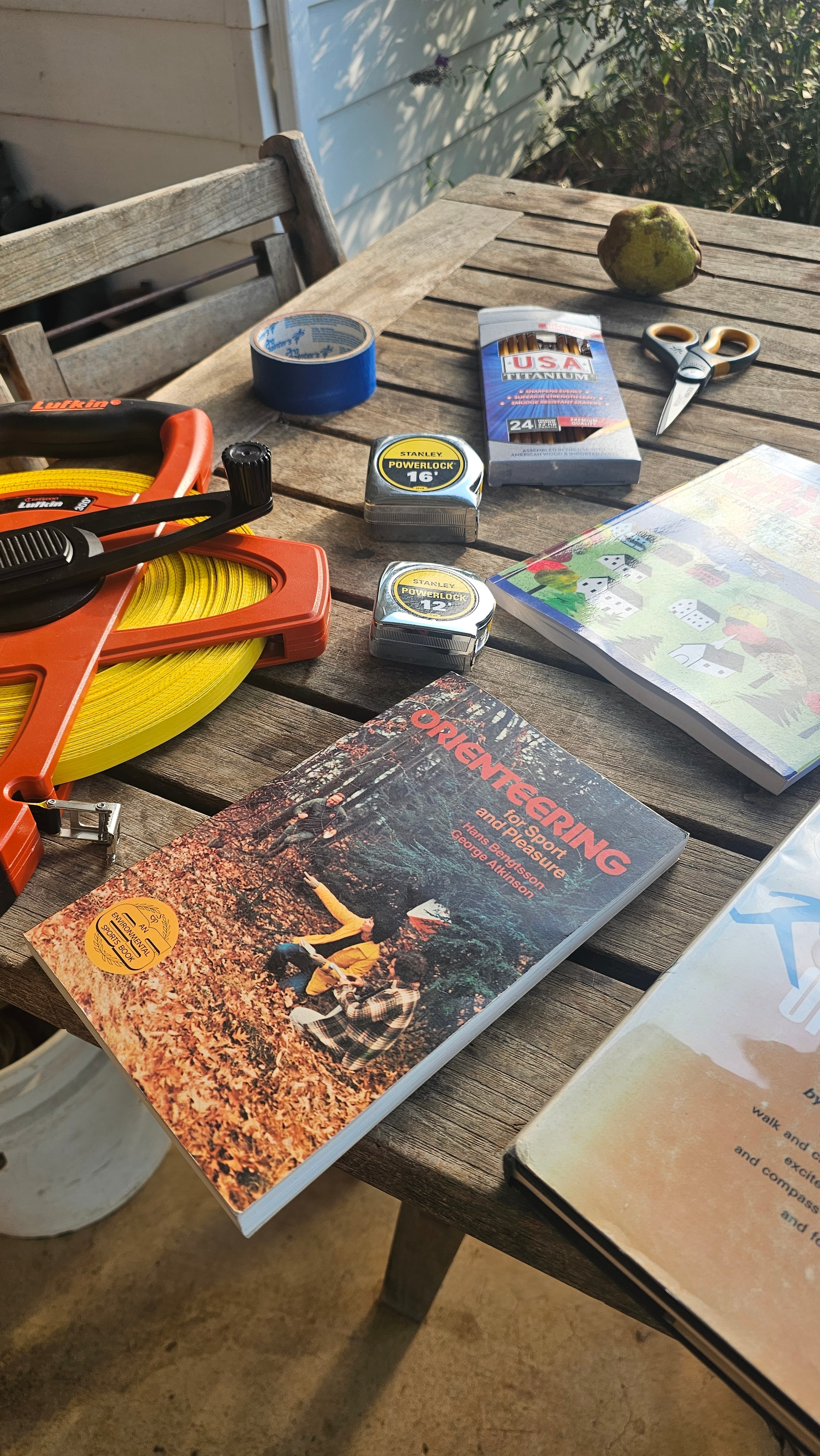 Orienteering tools, measuring tapes, and books laid out on an outdoor table
